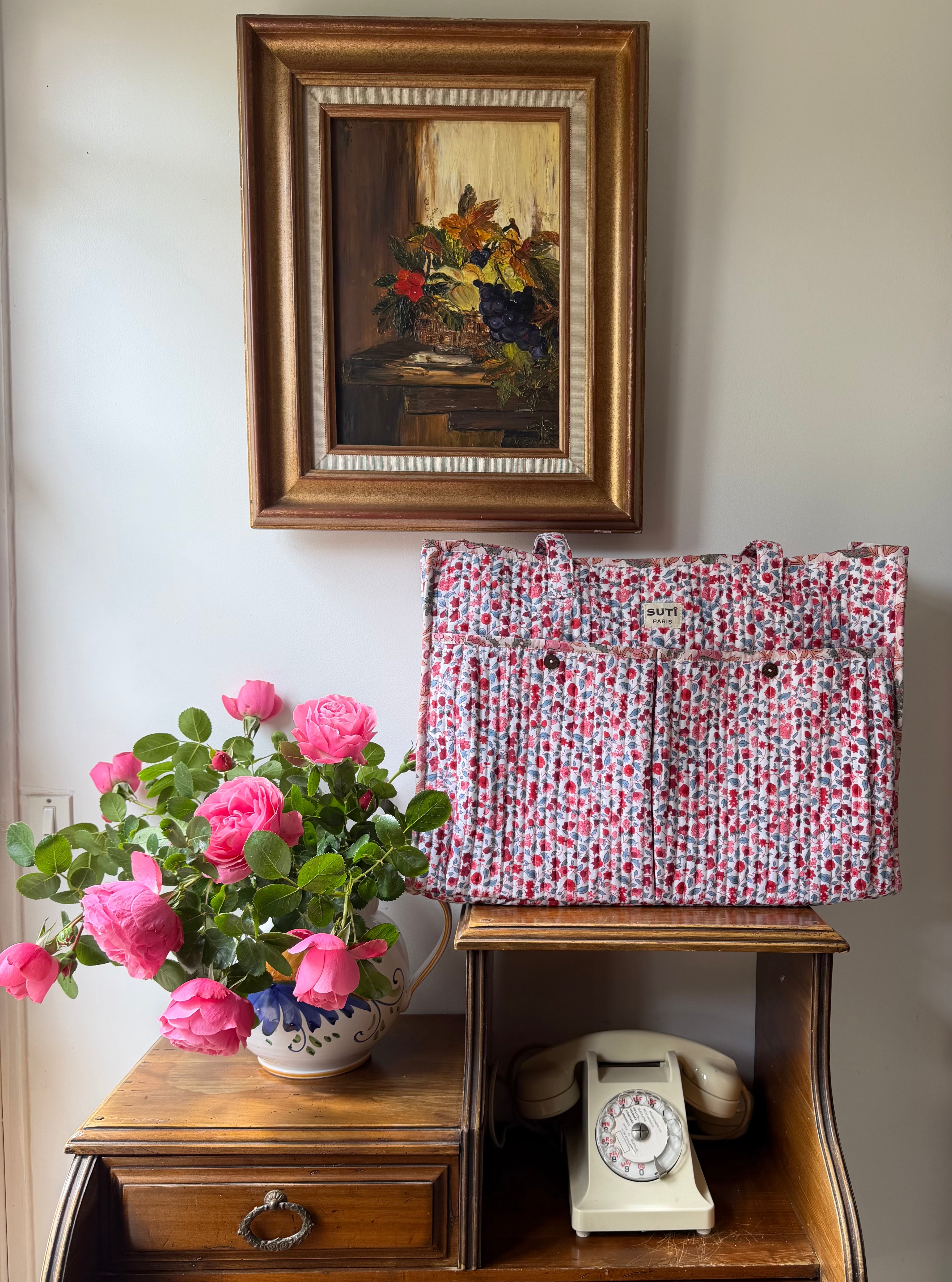 Vintage-style interior with a framed painting, floral arrangement, and old phone.